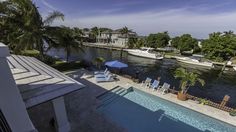 an outdoor swimming pool with lounge chairs next to it and boats on the water in the background