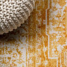 an orange and yellow rug with a knitted ball on it's bottom corner