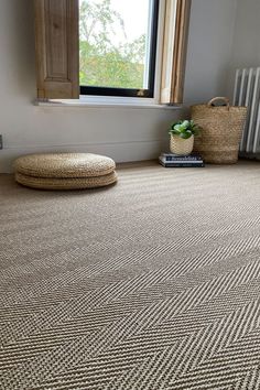 a carpeted room with a window and some books on the floor next to it