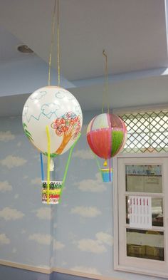 two hot air balloons hanging from the ceiling in a children's playroom with wallpaper