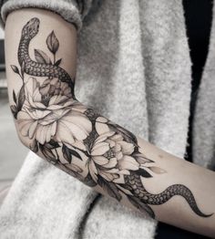 a woman's arm with flowers and a snake tattoo on the left side of her arm