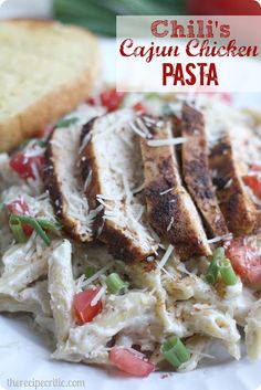 chicken pasta on a plate with bread and tomatoes