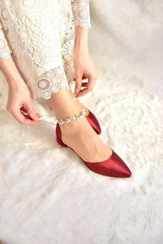 a woman in red shoes is tying her shoelaces on white furnishing