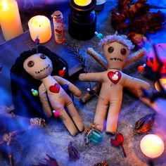 two voodoo dolls sitting next to each other in front of candles