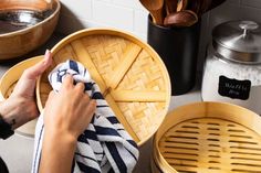 a woman is drying her hands on a dish towel in a wooden basket next to other dishes and kitchen utensils