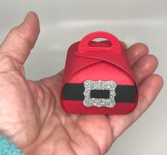 a hand holding a small red case with silver glitter on it