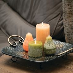 three candles are sitting on a tray next to a vase