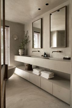 a large bathroom with two sinks and mirrors on the wall next to it's bathtub