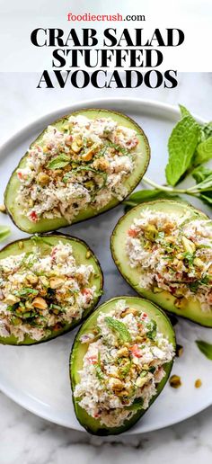 four stuffed avocados on a white plate with herbs and garnishes