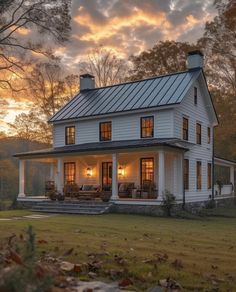 a white house sitting in the middle of a field with trees and grass around it