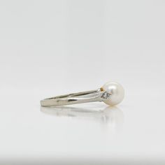 A fine Retro signed pearl cocktail ring.  In 14k white gold.  Set with 7mm round white pearl and flanked by two small accent diamonds on the shoulder of the setting.  Marked to the shank for Rothman & Schneider of New York City.  Simply a wonderful Mid-Century ring!  Date: Mid-20th Century  Overall Condition: It is in overall good, as-pictured, used estate condition with some fine & light surface scratches and other signs of expected light wear consistent with age.  Fineness: Marked 14k for gold Formal White Pearl Ring, White Diamond Pearl Drop Ring, White Pearl Diamond Ring With Pearl Drop, White Pearl Ring With Diamond, White Pearl Drop Ring For Formal Occasions, Classic White Pearl Ring, Classic White Pearl Ring With Drop Detail, Classic White Pearl Ring With Diamond Accents, Formal White Akoya Pearl Ring