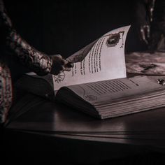 a person sitting at a table with an open book in front of them on top of a wooden table