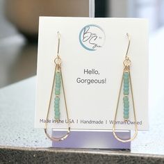 a pair of earrings is displayed on a card