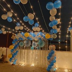 blue and white balloons are hanging from the ceiling