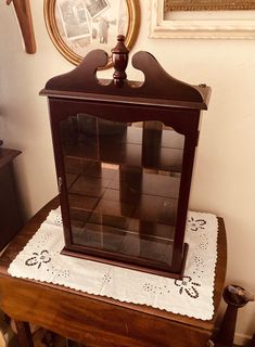 an old fashioned clock sitting on top of a wooden table in front of a mirror