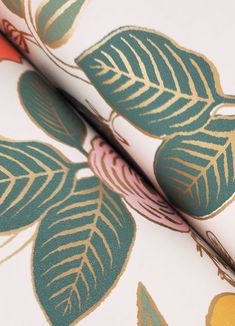 a close up view of a wallpaper with leaves on it and a pair of scissors in the foreground