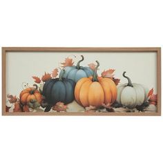 a painting of pumpkins and leaves in a wooden frame on a white wall behind it