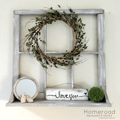 an old window frame with a wreath on top and some other items in the bottom