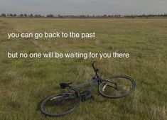 a bike laying in the middle of a field with a quote on it that reads, you can go back to the past but no one will be waiting for you there