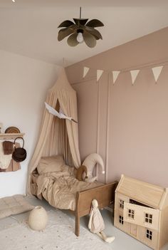 a child's bedroom with pink walls and white carpeted flooring, including a doll house on the bed