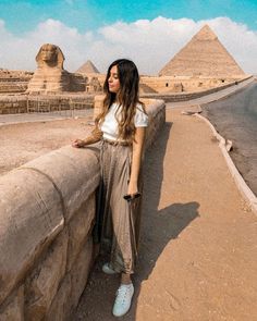 a woman leaning against a wall near the pyramids