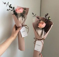 two flowers are wrapped in brown paper and tied with twine to hang on the wall