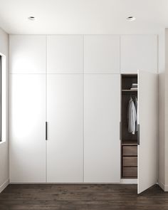 an empty closet with white walls and drawers in the corner, next to a window