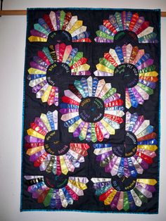 a quilted wall hanging with colorful ribbons on it