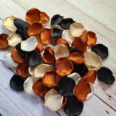 a pile of black, white and orange flowers on a wooden table with one flower in the middle