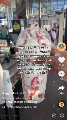 a person holding up a cup with whipped cream and strawberries in it on the screen