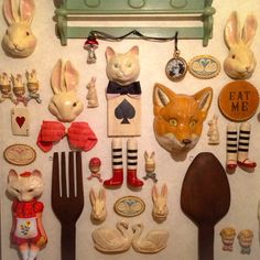 an assortment of kitchen utensils are displayed on a wall with bunny and cat figurines