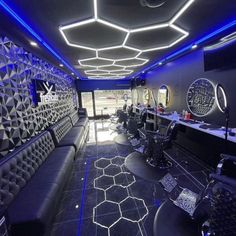 the interior of a salon with black and white furniture, blue lighting, and circular mirrors