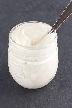 a glass jar filled with mayonnaise sitting on top of a table next to a spoon