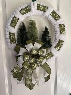 a wreath is hanging on the door with snowflakes and christmas trees in it