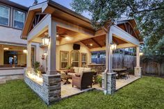 an outdoor living area with patio furniture and lighting on the side of the house, surrounded by grass