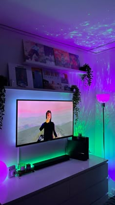 a flat screen tv sitting on top of a white table in a living room next to a plant