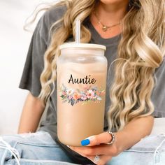 a woman sitting on the floor holding a drink in her hand and smiling at the camera