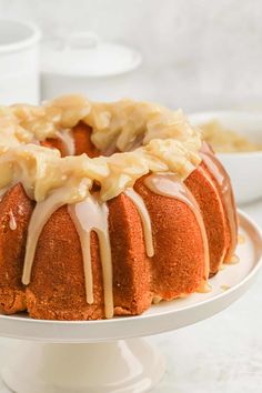 a bundt cake covered in icing on a white plate with another bundt cake behind it