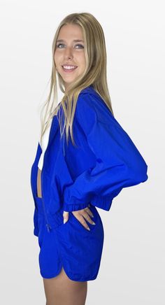 Lightweight fashion. This hooded crop jacket is a perfect addition for the right amount of comfort. The jacket has a front zipper and drawstring neckline at the hood with elastic bottom banding for a great fit. Pair it with matching shorts for the perfect outfit for active events. Color- Blue 100% Polyester Hooded Nylon Track Jacket, Spring Athleisure Track Jacket With Drawstring Hood, Spring Athleisure Nylon Hooded Jacket, Athleisure Hooded Windbreaker With Drawstring, Spring Sporty Track Jacket With Elastic Cuffs, Sporty Hooded Jacket With Zipper For Spring, Casual Nylon Hooded Jacket With Drawstring, Sporty Spring Hooded Jacket With Zipper, Athleisure Long Sleeve Windbreaker With Drawstring