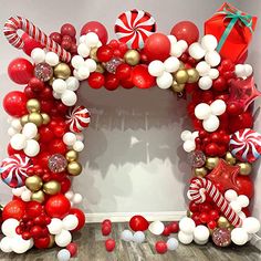 a red and white balloon arch decorated with candy canes, lollipops, and christmas decorations