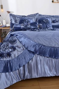 a blue comforter set with ruffled edges and flowers on the bottom, along with matching pillows