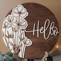 a wooden sign that says hello with flowers on it