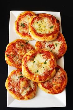 mini pizzas are arranged on a white plate