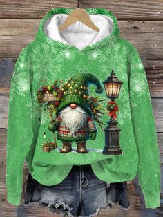 a green hoodie with an image of a santa clause on the front and christmas lights on