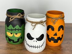 three painted mason jars decorated with halloween faces and jack - o'- lanternes