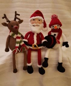 three knitted santa and reindeer dolls sitting next to each other on a white surface