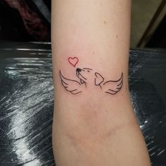 a small tattoo on the ankle of a woman with two doves and a heart