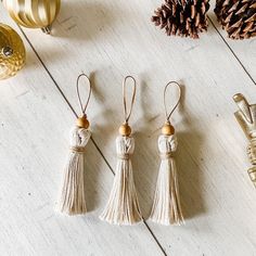 three small tasseled ornaments are sitting on a table next to pine cones and other holiday decorations