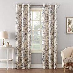 a living room filled with furniture and a large window covered in white floral curtains next to a wooden floor