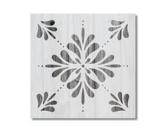 a white and black wall hanging with an ornate design on the wood paneled surface